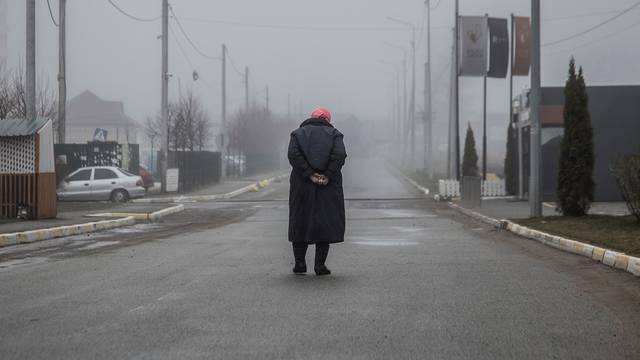 Local woman walks along an empty street in the town of Bucha