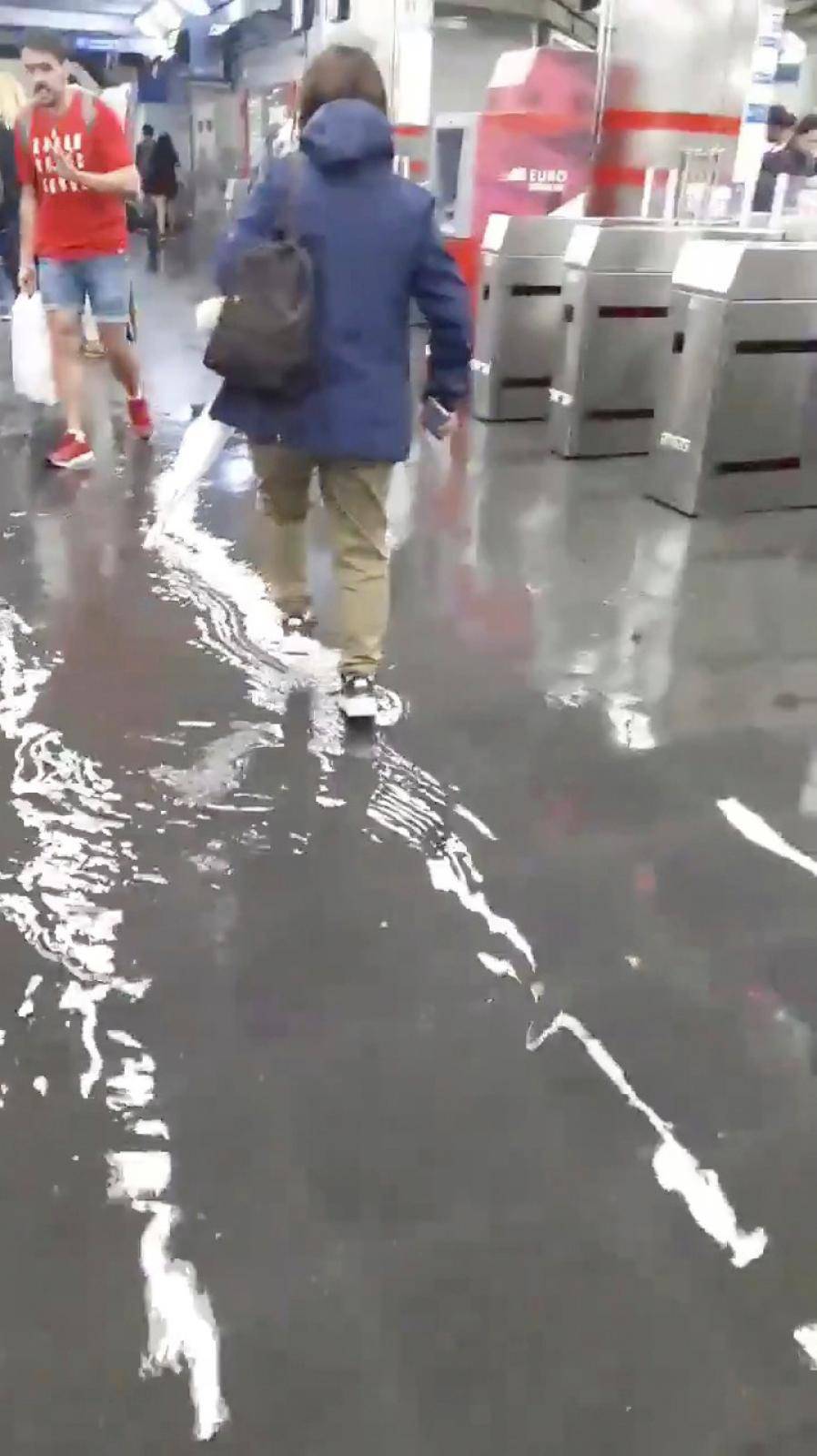People walk in a partially flooded metro station in Madrid's downtown