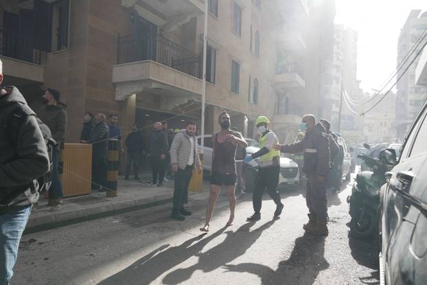 A man runs along a street among members of the Lebanese Civil Defence and civilians following an Israeli air strike in Beirut