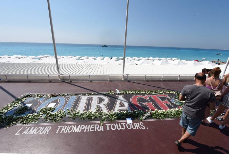 Tourists walk along the Promenade des Anglais as part of the commemorations of last year's July 14 fatal truck attack on the Promenade des Anglais in Nice