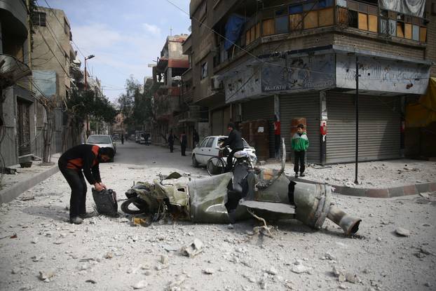 People inspect missile remains in the besieged town of Douma, in eastern Ghouta, in Damascus