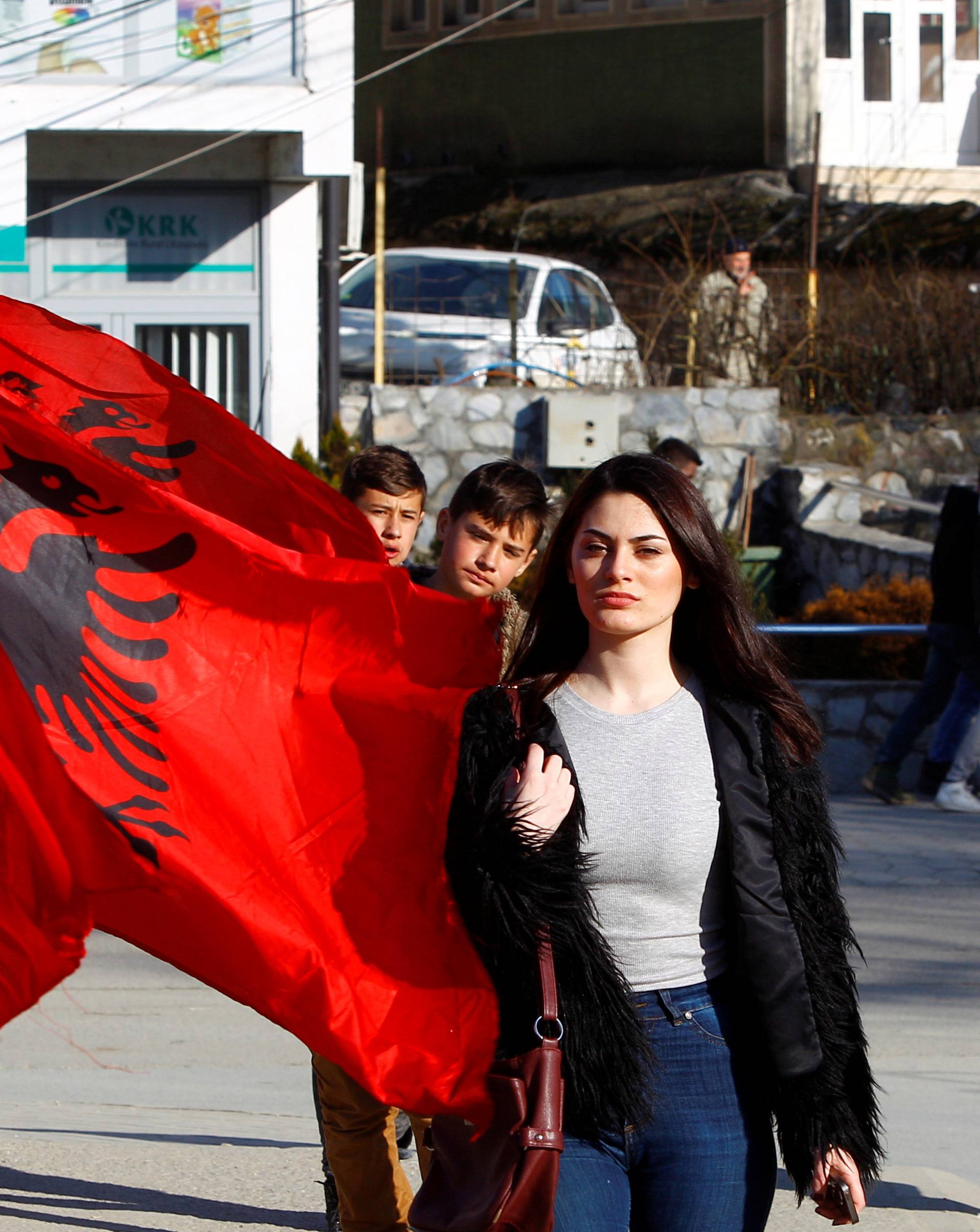 A girl passes next to Albanian flags ahead of tomorrow's 10 year independence celebration in Kacanik