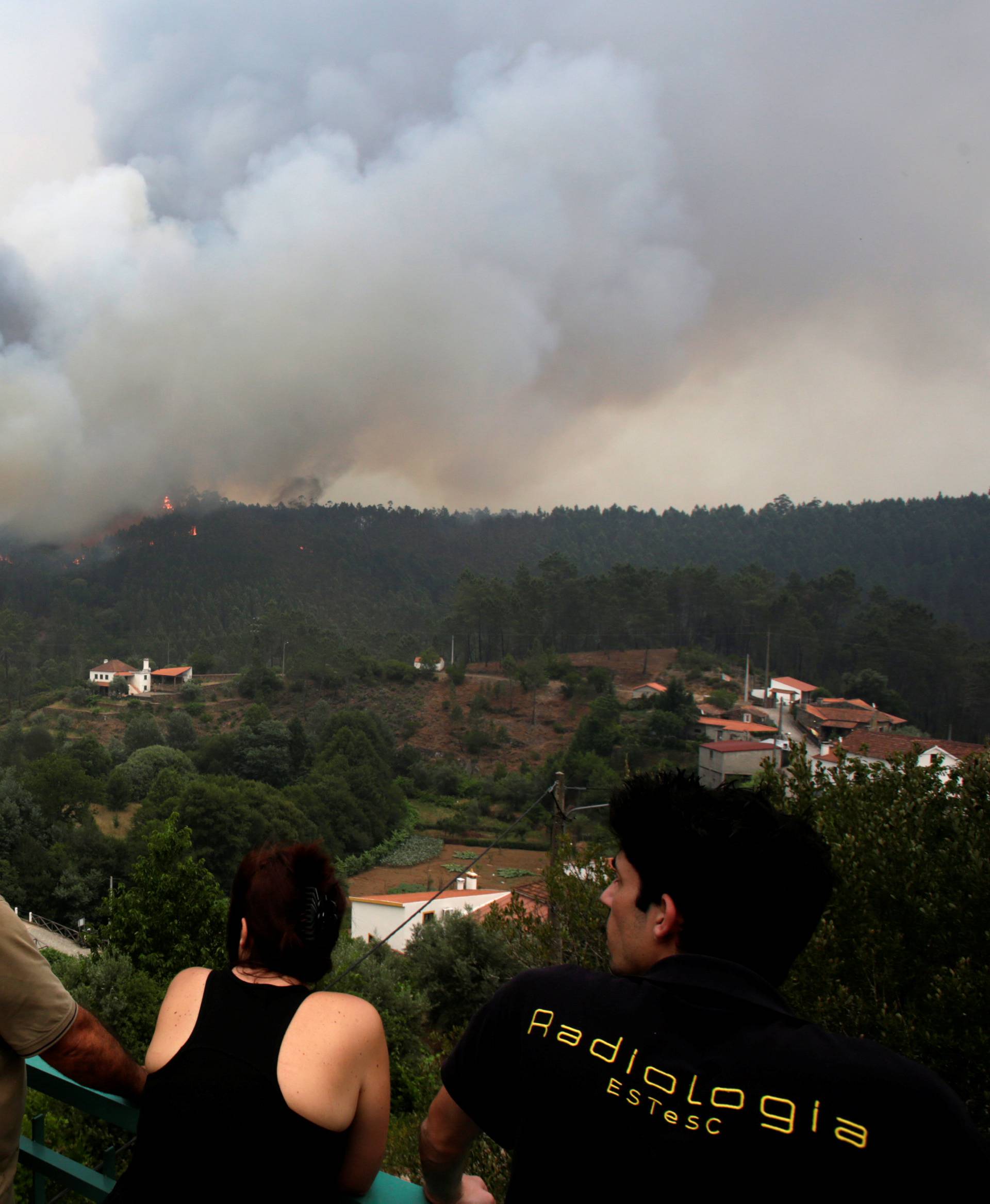 People look at fire and smoke during a forest fire in Pedrogao Grande