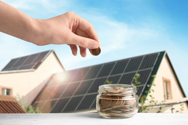 Woman,Putting,Coin,Into,Jar,Against,House,With,Installed,Solar