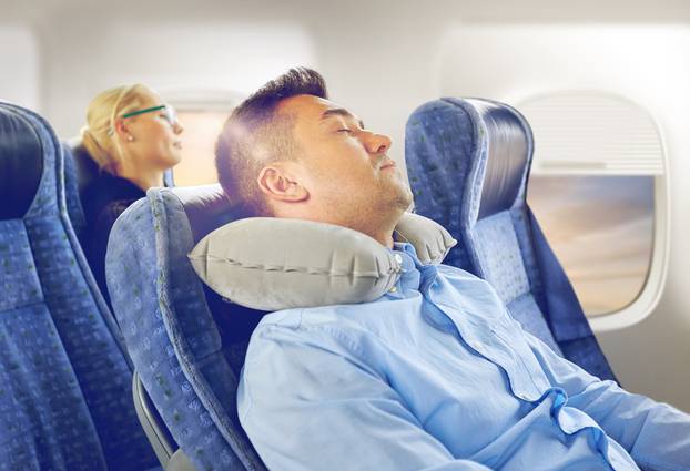 man sleeping in plane with cervical neck pillow