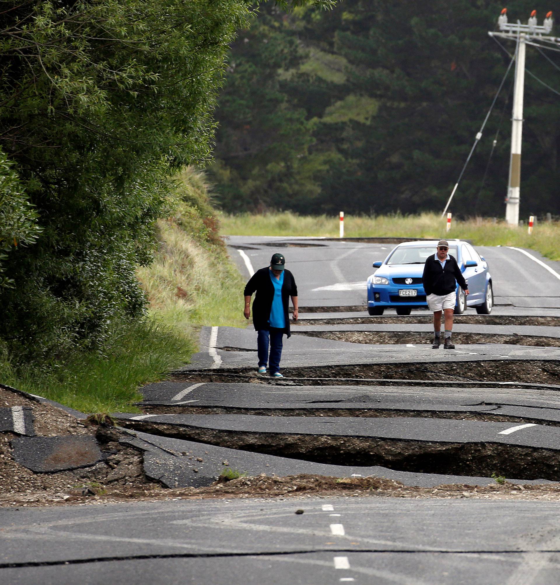 Local residents Chris and Viv Young look at damage caused by an earthquake along State Highway One near the town of Ward, south of Blenheim on New Zealand's South Island