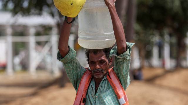 Labourer carries container filled with water in New Delhi