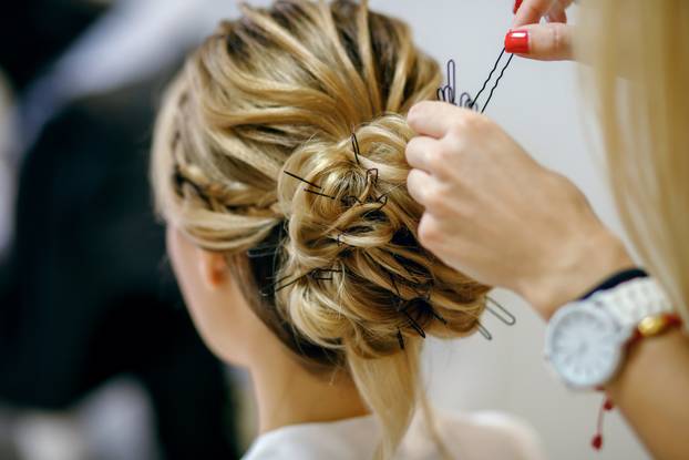 Professional hairdresser with red manicure doing her hair in the women's salon