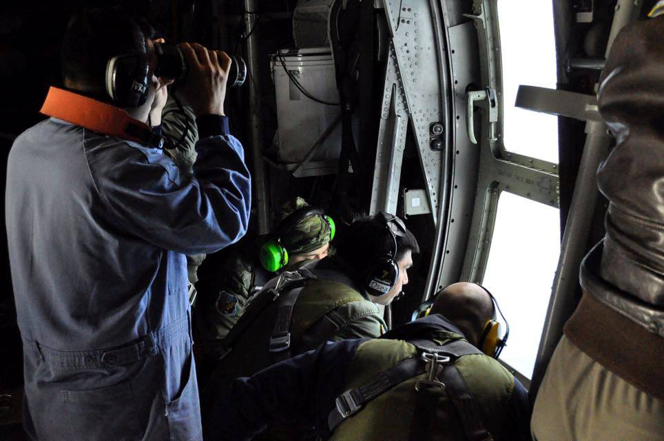 Members of the Argentine Navy look down at the sea from an airplane during a flight to search for the ARA San Juan submarine missing at sea