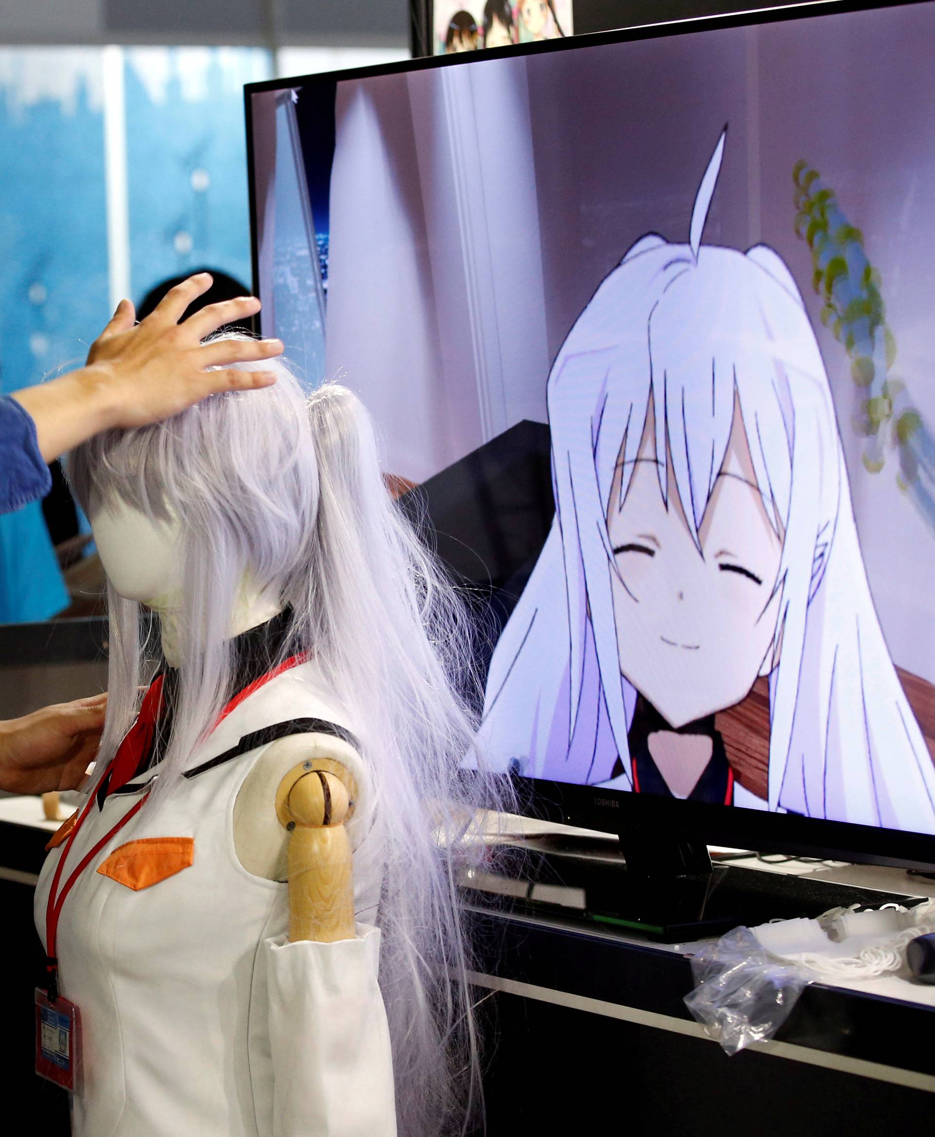 A man touches a mannequin as he tries out a M2 Co.Ltd's "E-mote" system as the monitor shows the image from the VR device at Tokyo Game Show 2016 in Chiba