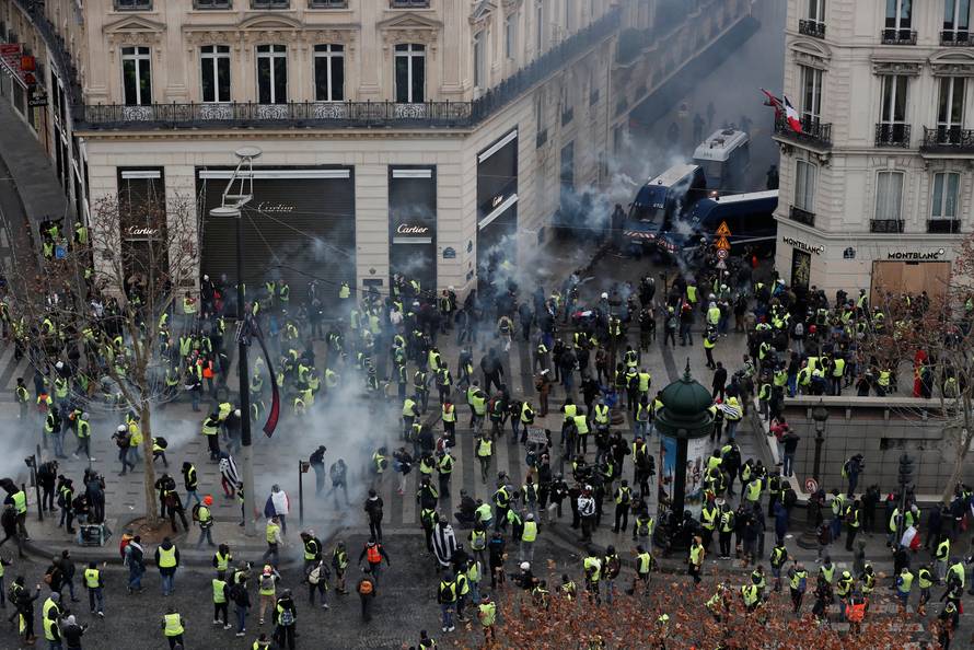Protesters wearing yellow vests face off with French Gendarmes on the Champs-Elysees Avenue during a demonstration by the "yellow vests" movement in Paris