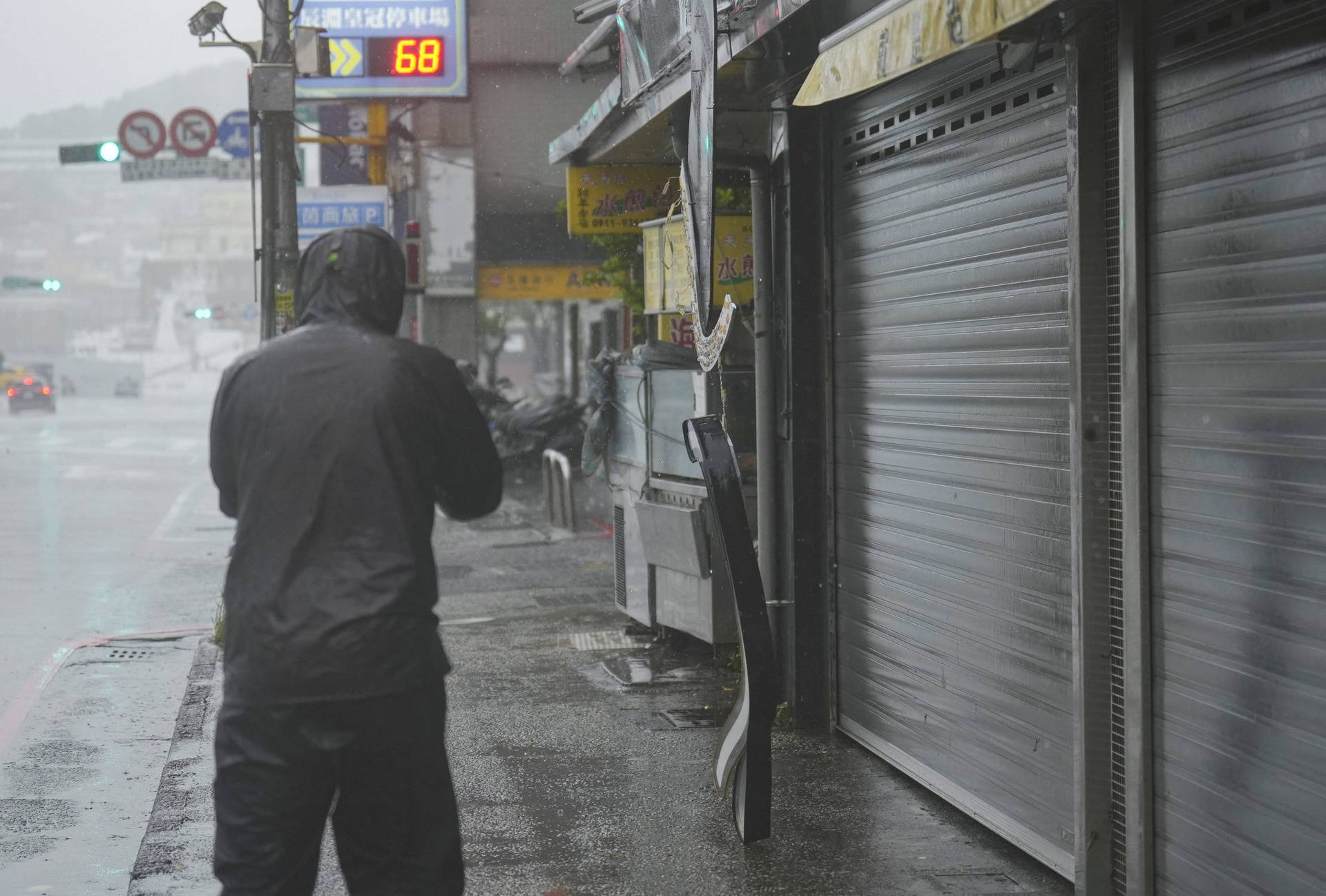 A person walks past a fallen light sign as Typhoon Kong-rey approaches in Keelung,