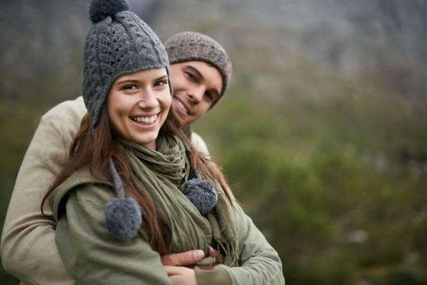 They love taking in the mountain views. A happy young couple enjoying the sights while hiking through the mountain.