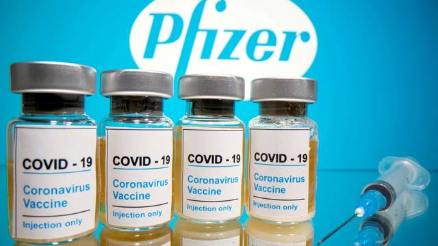 FILE PHOTO: Vials and medical syringe are seen in front of Pfizer logo in this illustration