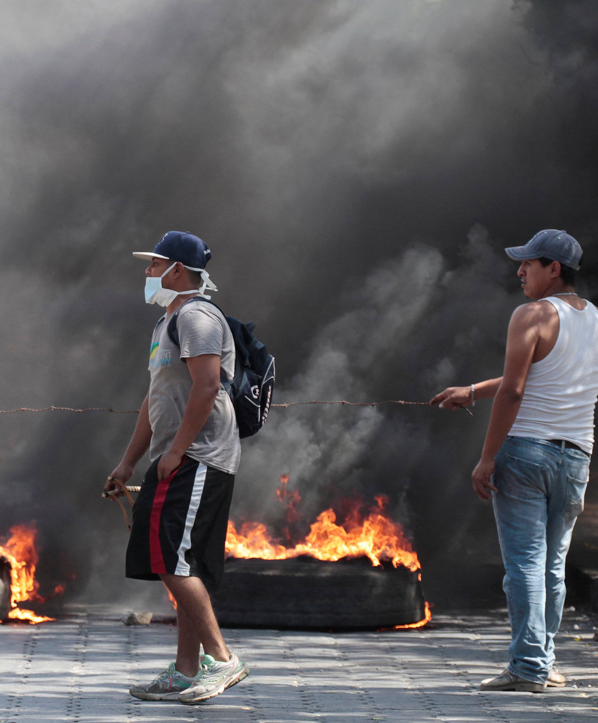 Demonstrators walk past a barricade as they take part during a protest, in Managua,