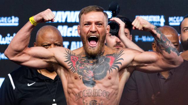 UFC lightweight champion Conor McGregor of Ireland poses on the scale during his official weigh-in at T-Mobile Arena in Las Vegas