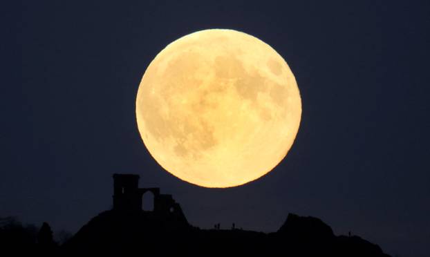 People watch as the Suoermoon, known as the Hunter’s moon rises over Mow Cop castle in Mow Cop, Britain