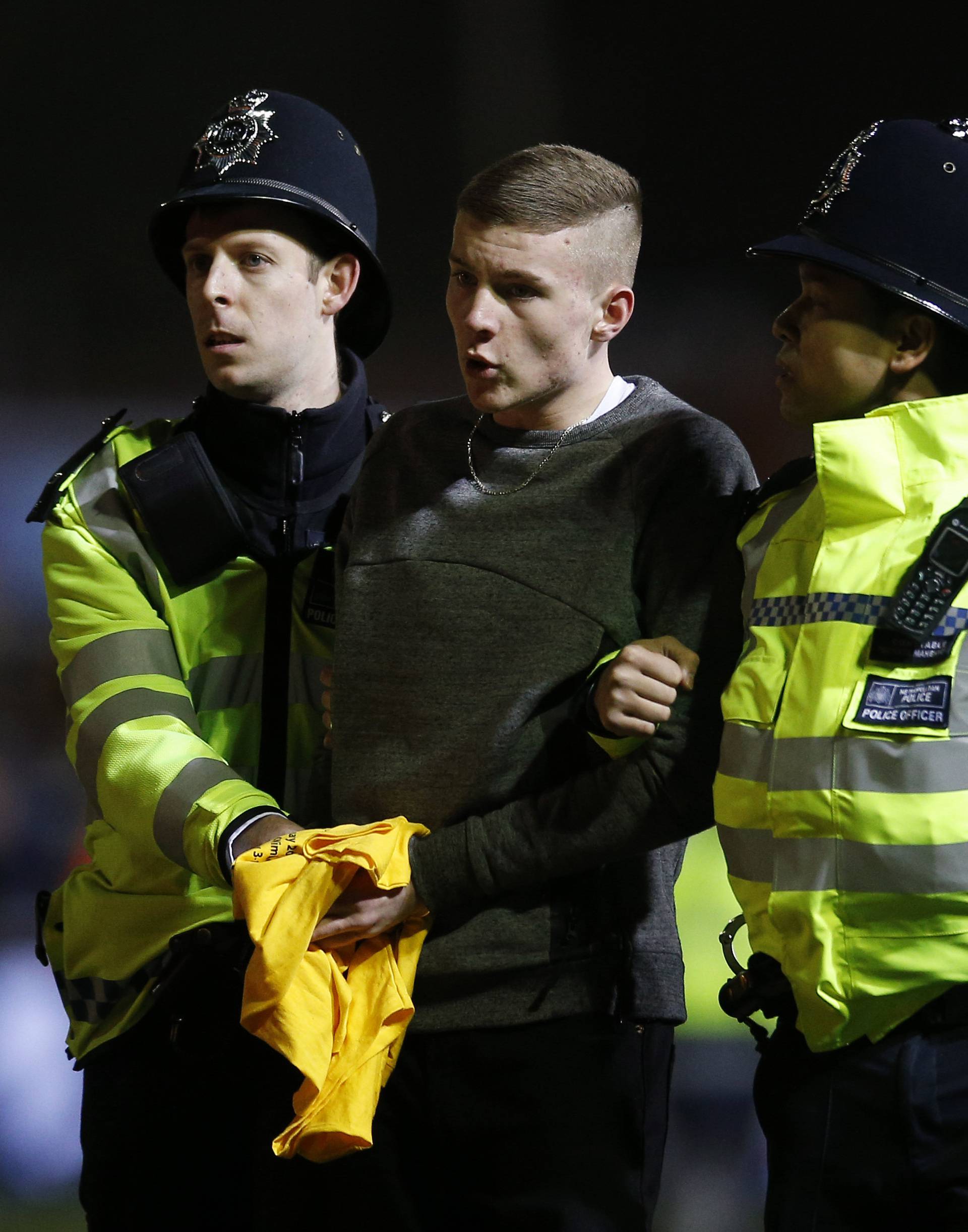 A Sutton fan on the pitch escorted by police officers after the match