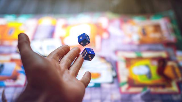 Hand,Throws,The,Dice,On,The,Background,Of,Colorful,Blurred