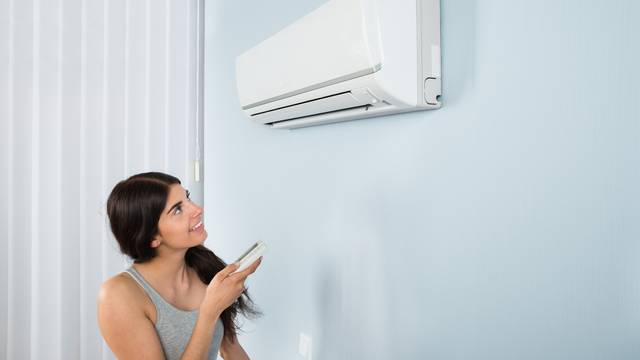 Woman Holding Remote Control Air Conditioner
