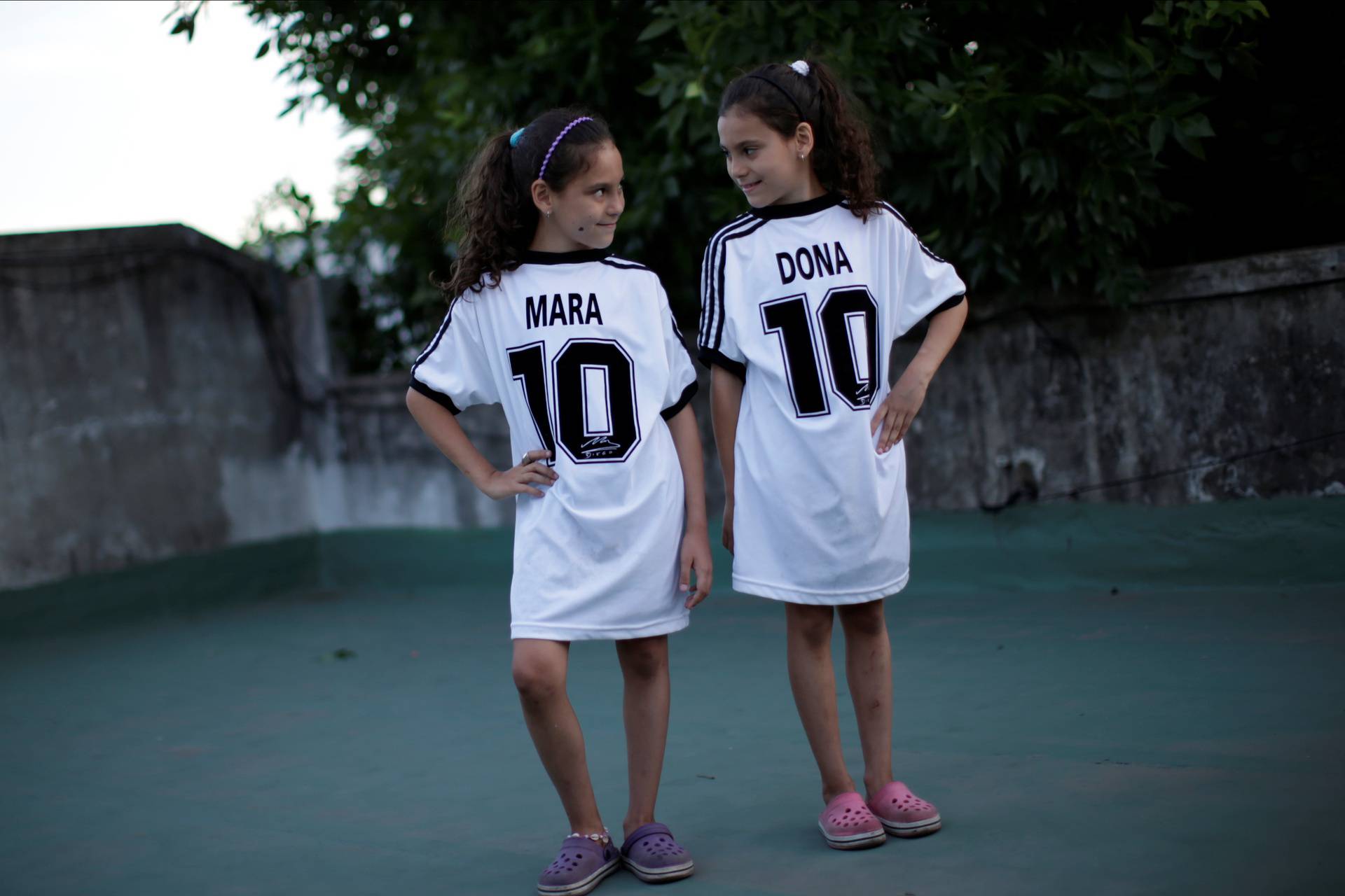 Mara and Dona, twin daughters of Walter Gaston Rotundo, a devoted Diego Maradona fan who named his daughters after the soccer star, pose for photos at their house, in Buenos Aires