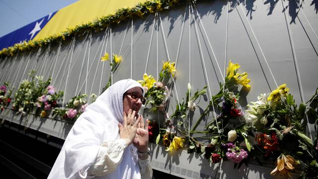 A woman reacts near a truck carrying coffins of newly identified victims of the 1995 Srebrenica massacre, in front of the presidential building in Sarajevo