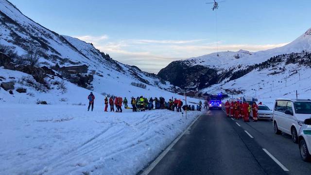 Rescue workers stand near the site where an avalanche buried 10 skiers in the Austrian ski resort of Lech