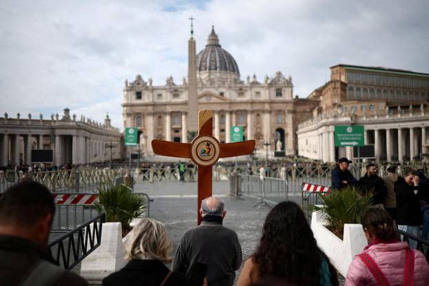 A pilgrim carries a cross as Pope Francis is admitted to continue treatment