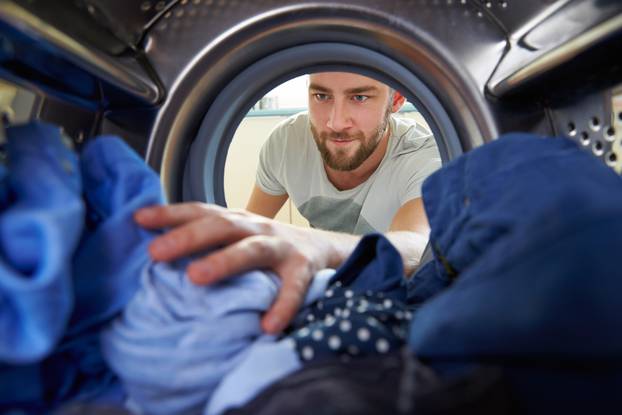 Man,Doing,Laundry,Reaching,Inside,Washing,Machine