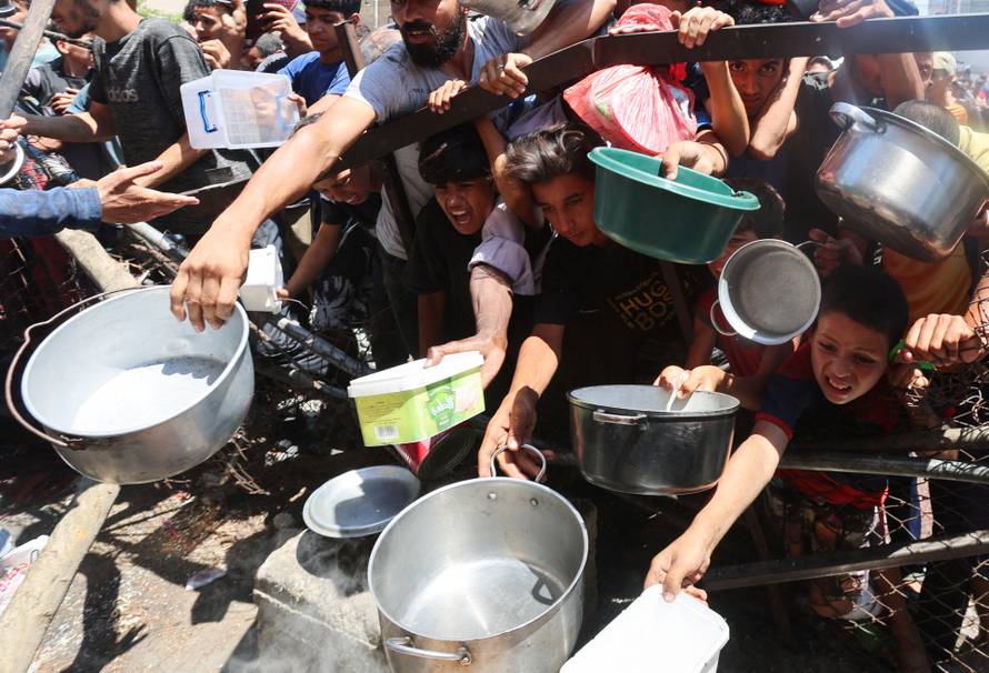 Palestinians gather to receive food from a charity kitchen, amid a hunger crisis, in Nuseirat