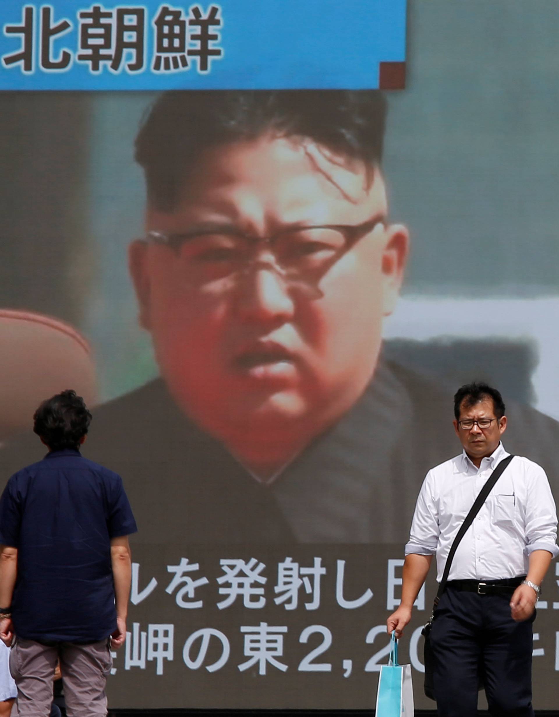 Passersby walk past a TV screen reporting news about North Korea's missile launch in Tokyo