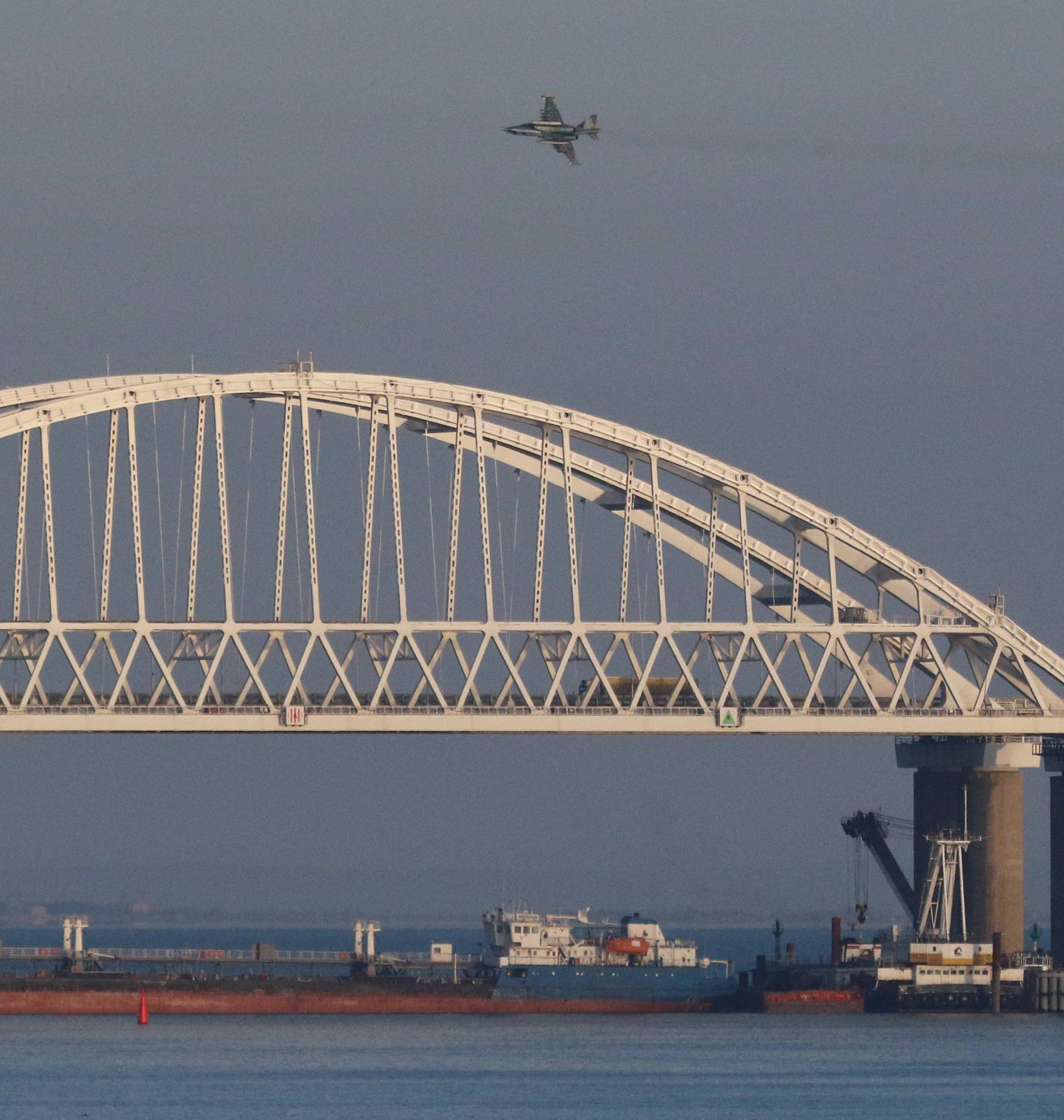 Russian jet fighters fly over a bridge connecting the Russian mainland with the Crimean Peninsula with a cargo ship beneath it after three Ukrainian navy vessels were stopped by Russia from entering the Sea of Azov via the Kerch Strait in the Black Sea