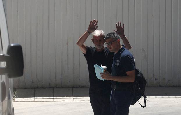 FILE PHOTO: British pensioner David Hunter waves at journalists while being escorted to a police van outside a courthouse in Paphos