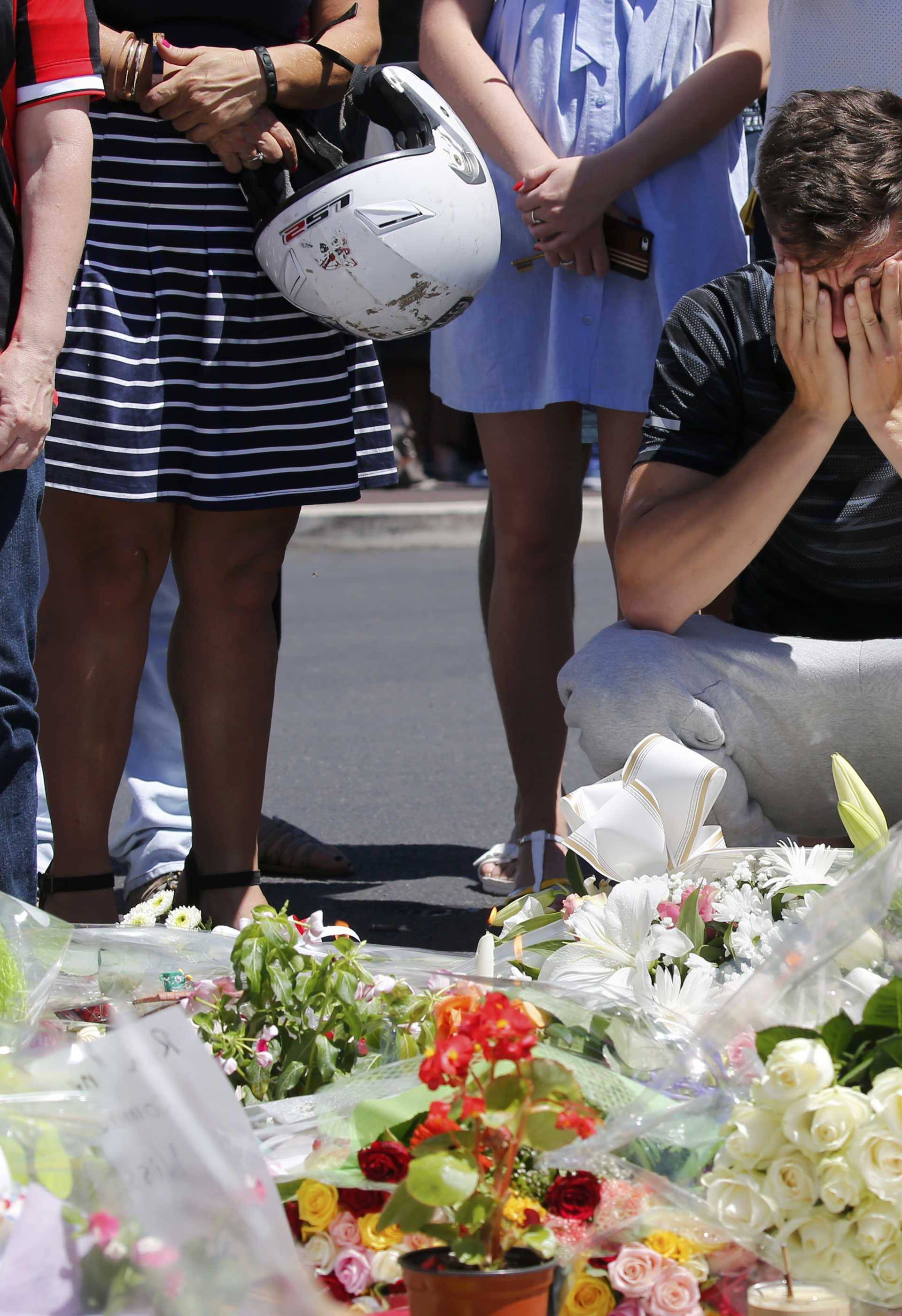 A man reacts near flowers placed in tribute to victims, two days after an attack by the driver of a heavy truck who ran into a crowd on Bastille Day killing scores and injuring as many, in Nice