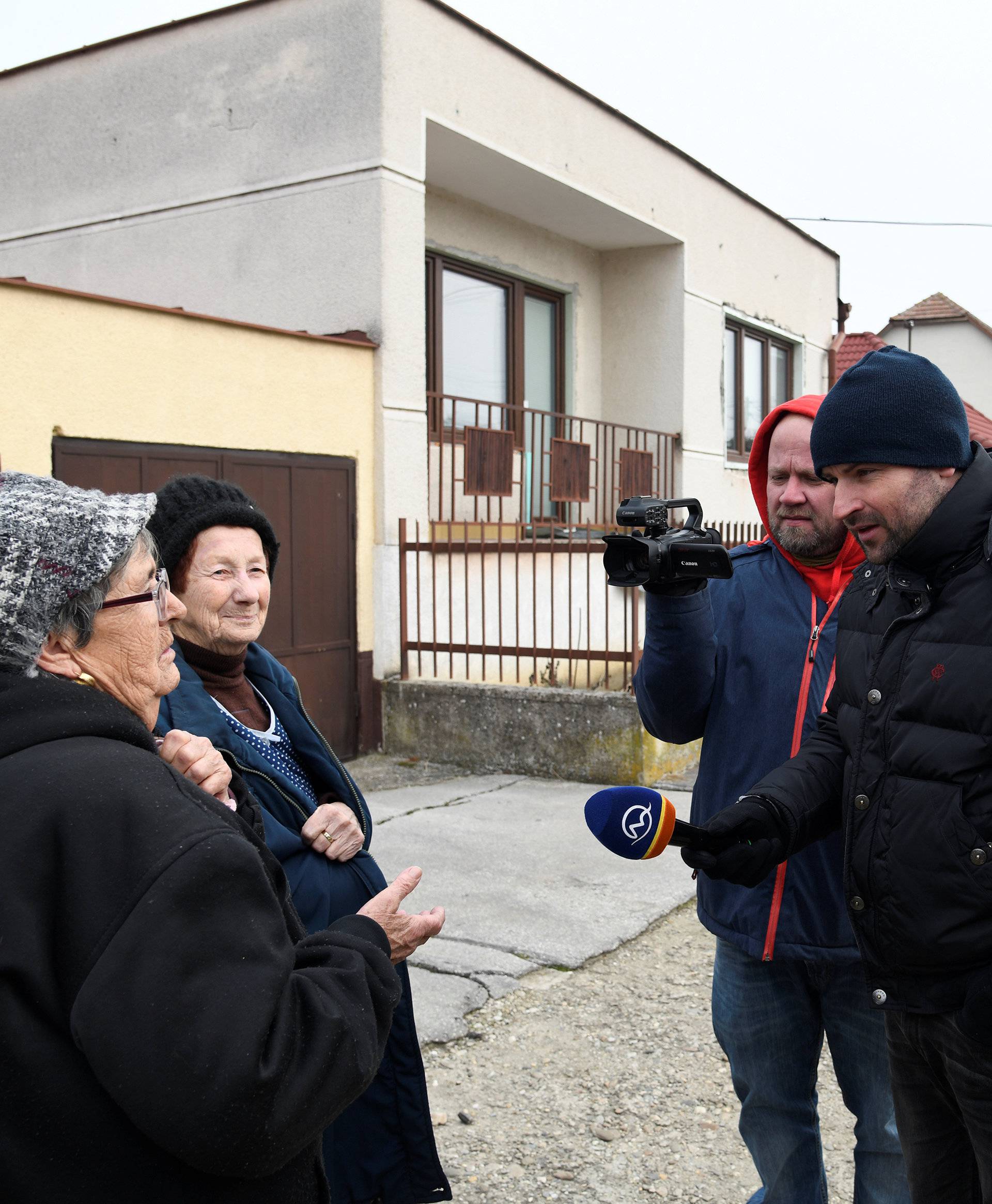 Neighbours Anna (L) and Maria speak to the media near to the house where Slovak investigative journalist Jan Kuciak and his girlfriend Martina Kusnirova lived and were murdered in the village of Velka Maca