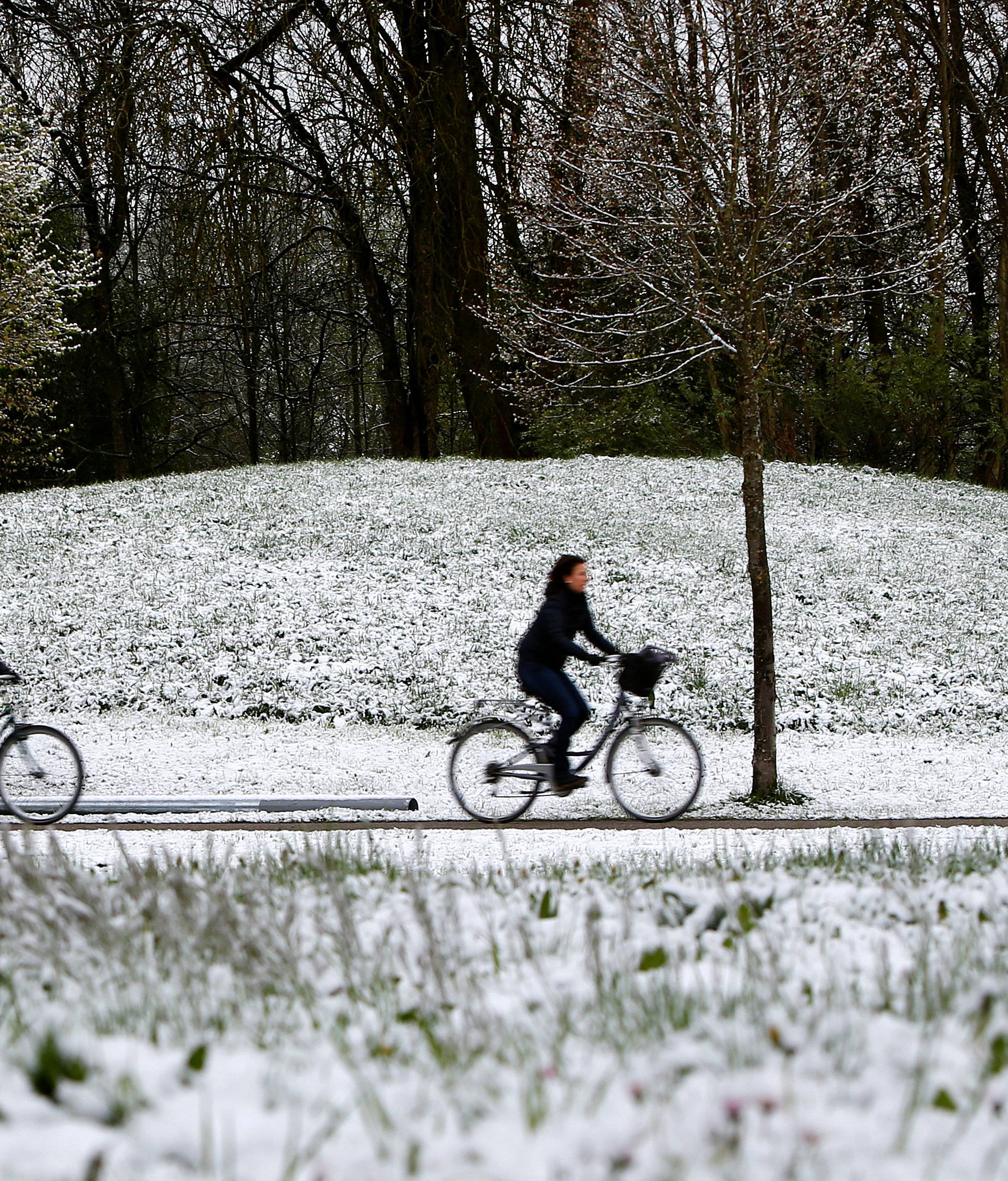 Cyclists pass snow-covered meadow in Eichenau