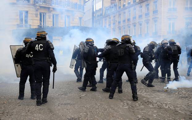 Riot policemen react to tear gas during a demonstration by the "yellow vests" movement in Paris