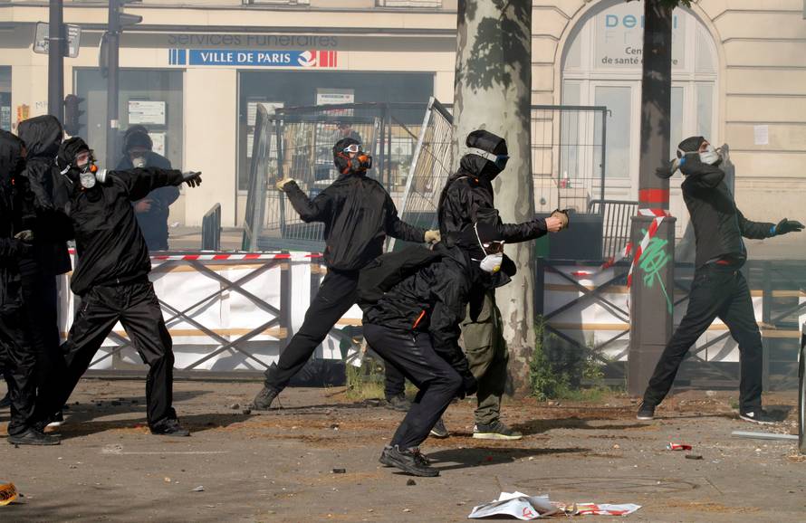 Tear gas floats around masked protesters during clashes with French CRS riot police at the May Day labour union rally in Paris