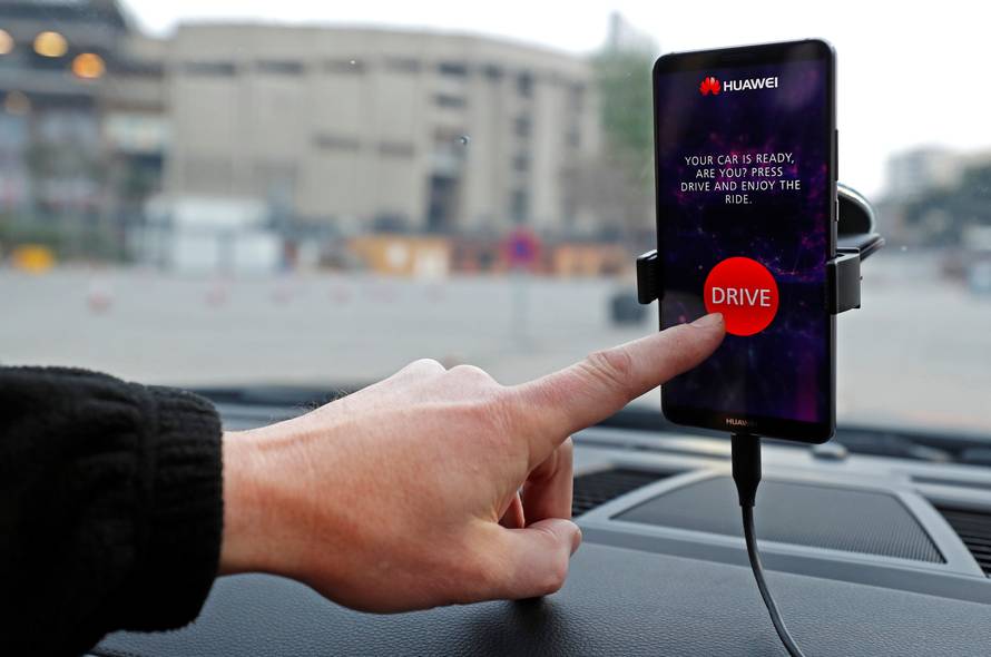 An engineer points to a Huawei Mate 10 Pro mobile used to control a driverless car during the Mobile World Congress in Barcelona