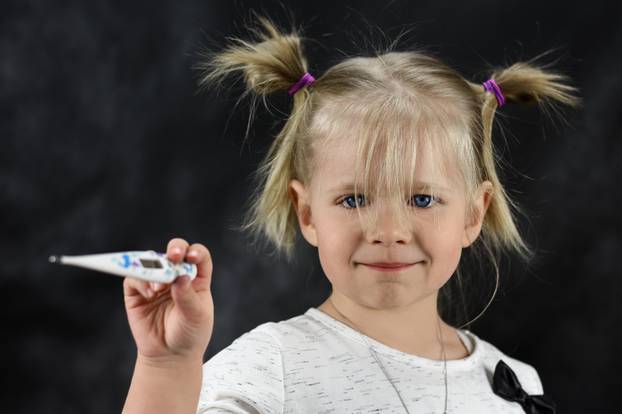 A sick child girl holding a thermometer in her hand