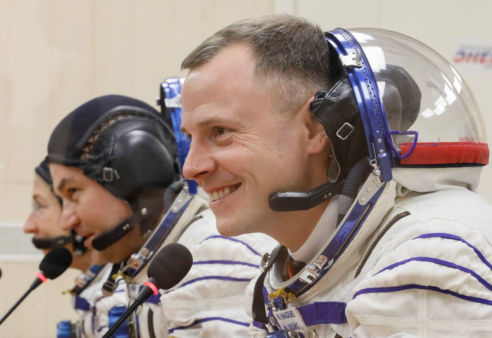 The International Space Station (ISS) crew members talk after donning space suits shortly before their launch at the Baikonur Cosmodrome
