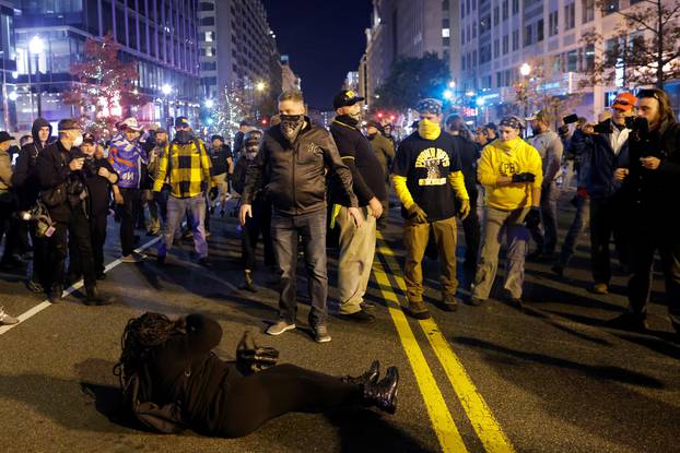A woman lies on the ground surrounded by members of far-right militia Proud Boys during a scuffle following a protest against election results, in Washington, U.S.