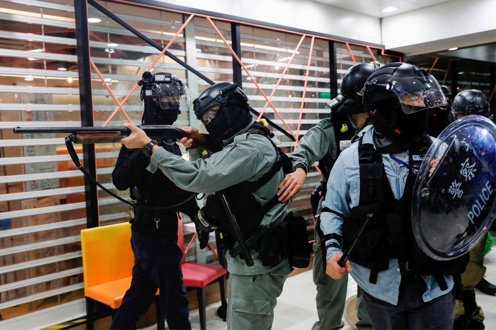 Riot police hold a rifle as they disperse anti-government protesters at shopping mall in Tai Po, Hong Kong