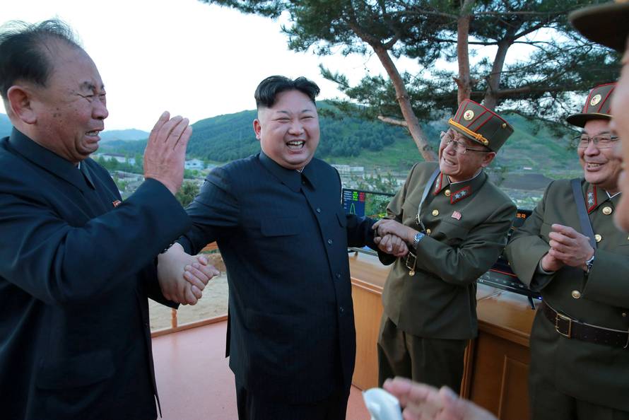 North Korean leader Kim Jong Un reacts with members of the Korean People's Army scientists and engineers