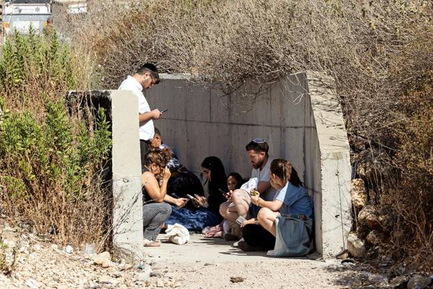 Israelis take shelter at the side of a highway as siren sounds following missile attack from Iran on Israel, in central Israel