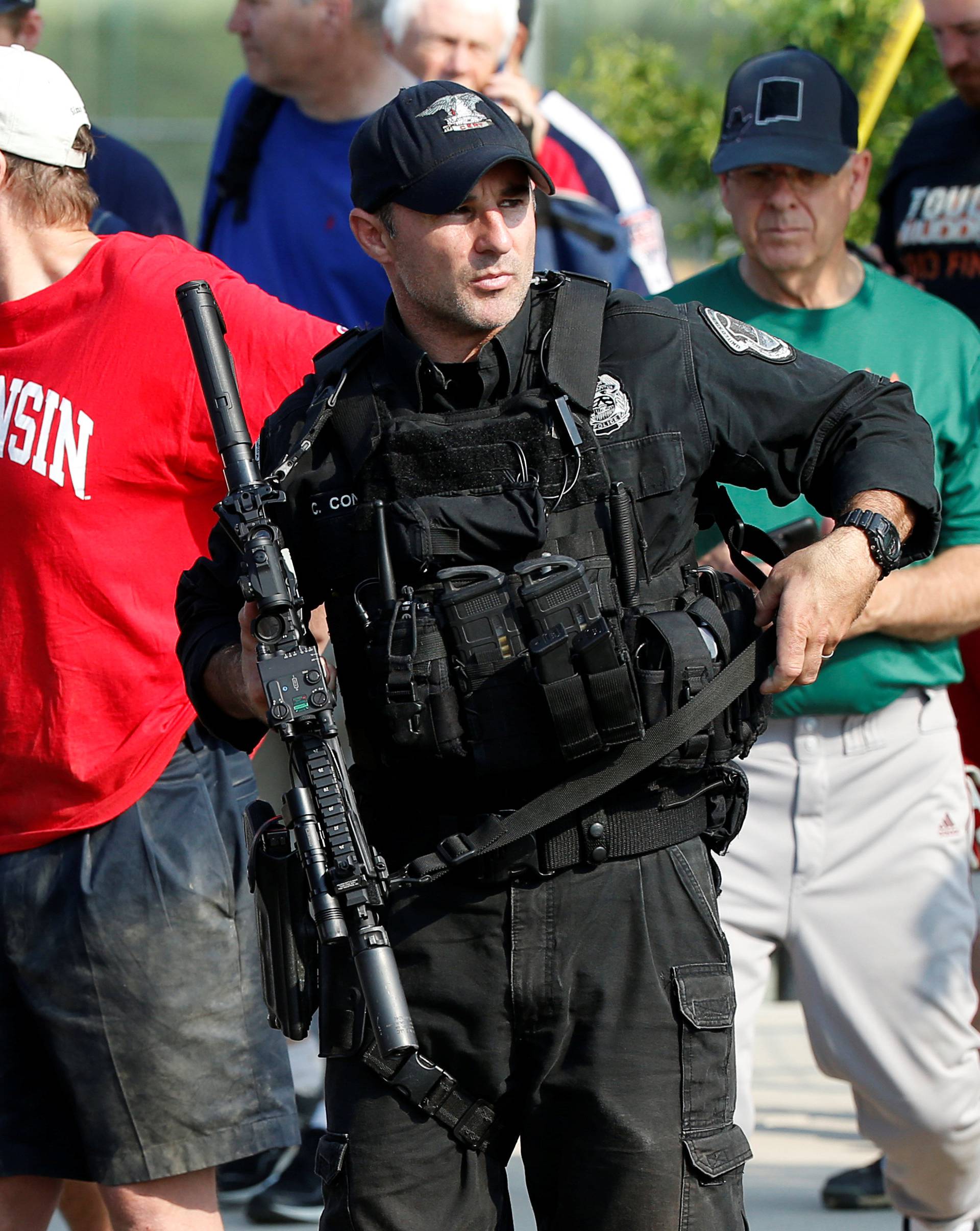 A police officer escorts members of Congress and staff from the scene after a gunman opened fire on members of Congress during baseball practice in Alexandria, Virginia
