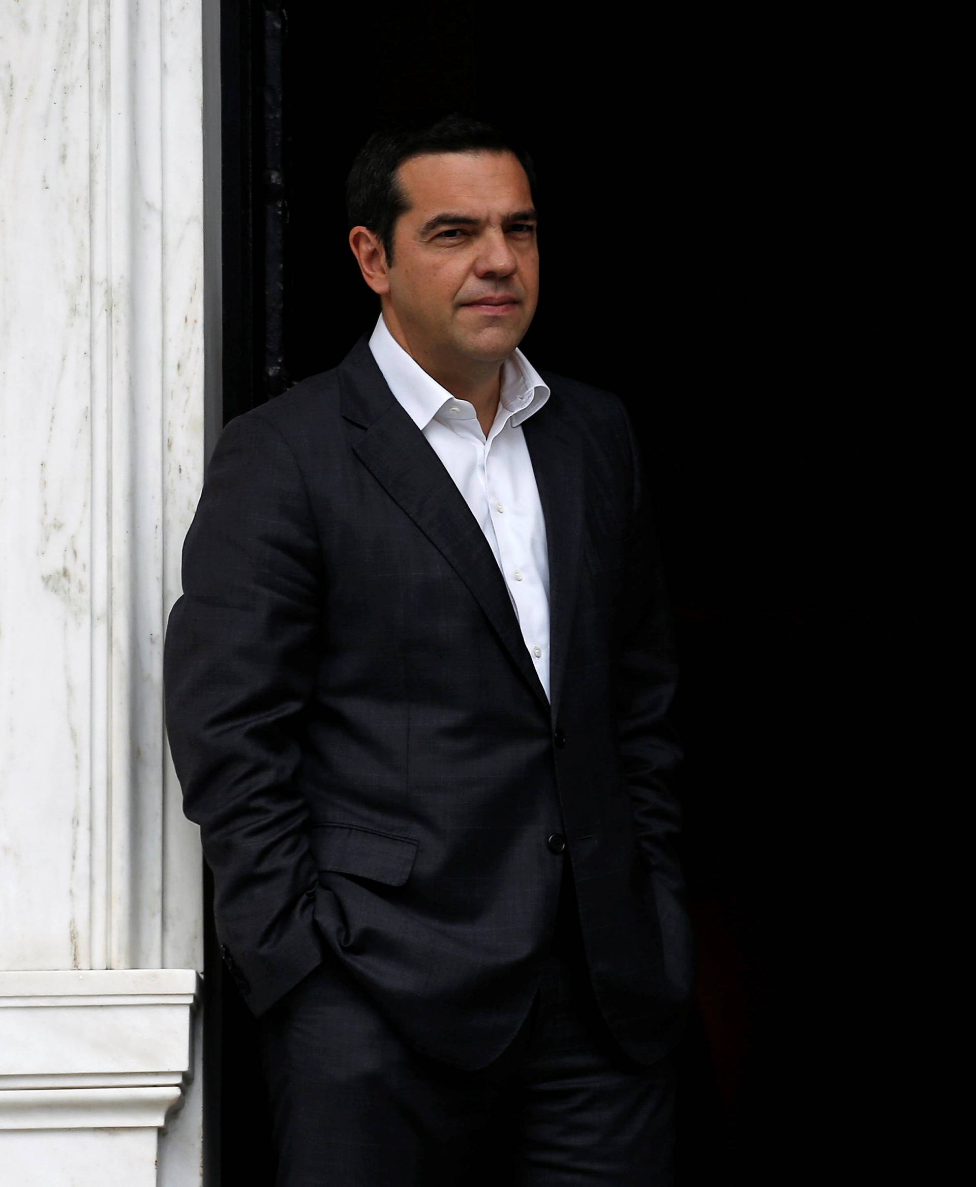 Greek Prime Minister Alexis Tsipras waits for former French President Francois Hollande at his office in the Maximos Mansion in Athens