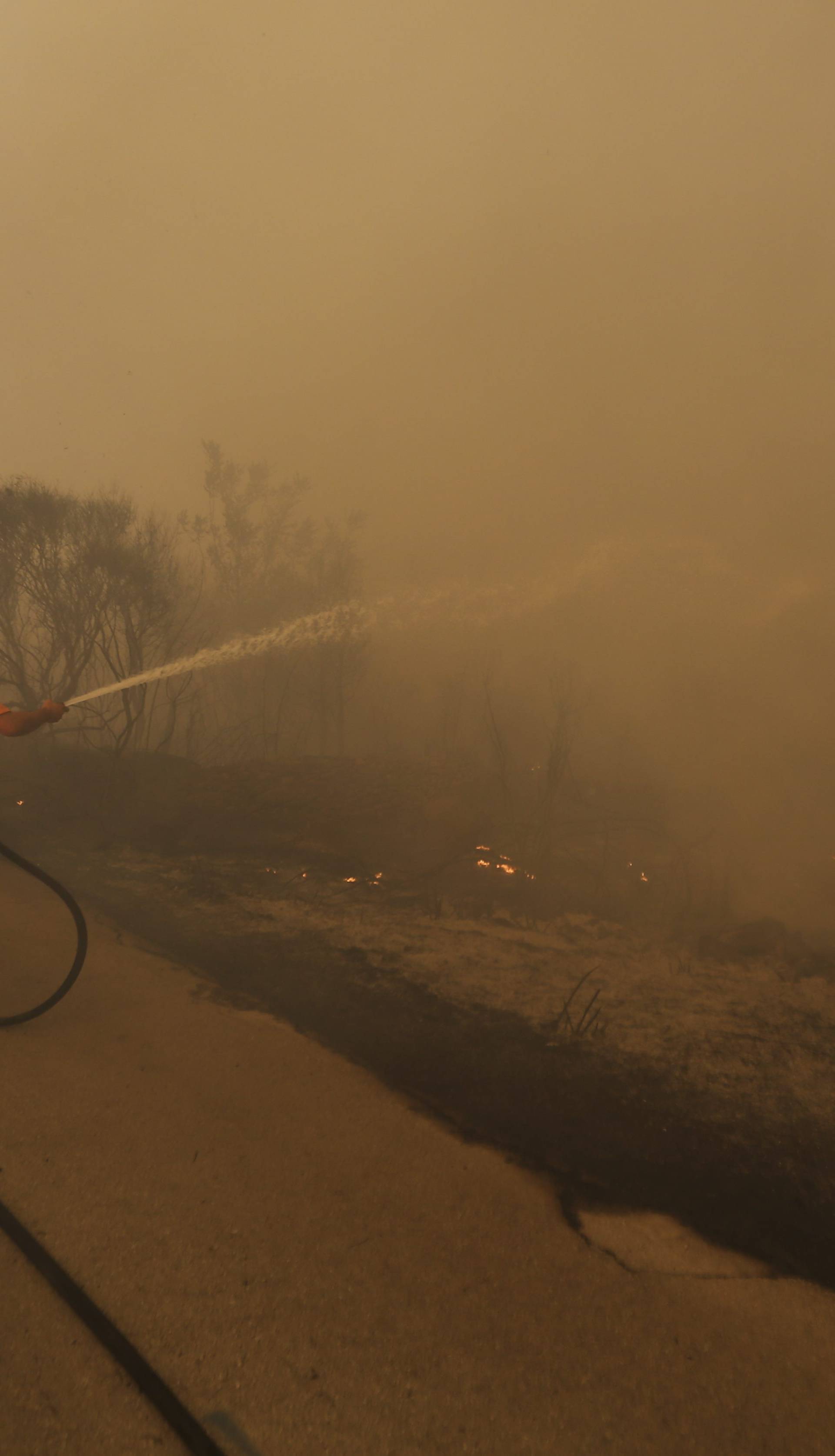 A local resident holds a hose as he tries to extinguish a wildfire in the village of Mravinc near Split