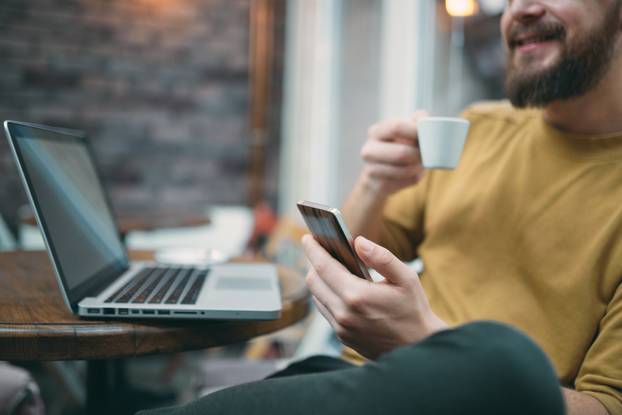 Young man sitting in cafe and using smart phone.