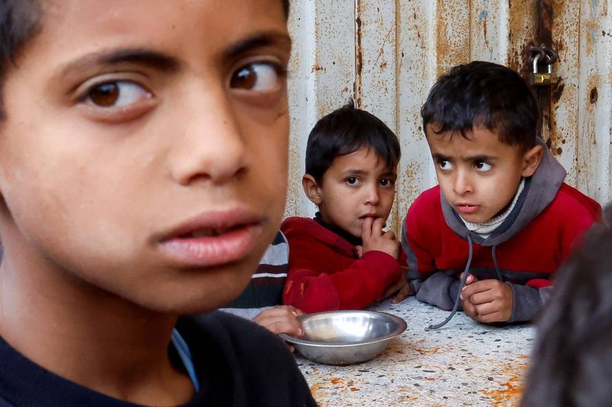 FILE PHOTO: Palestinians gather to receive food cooked by a charity kitchen, in Khan Younis